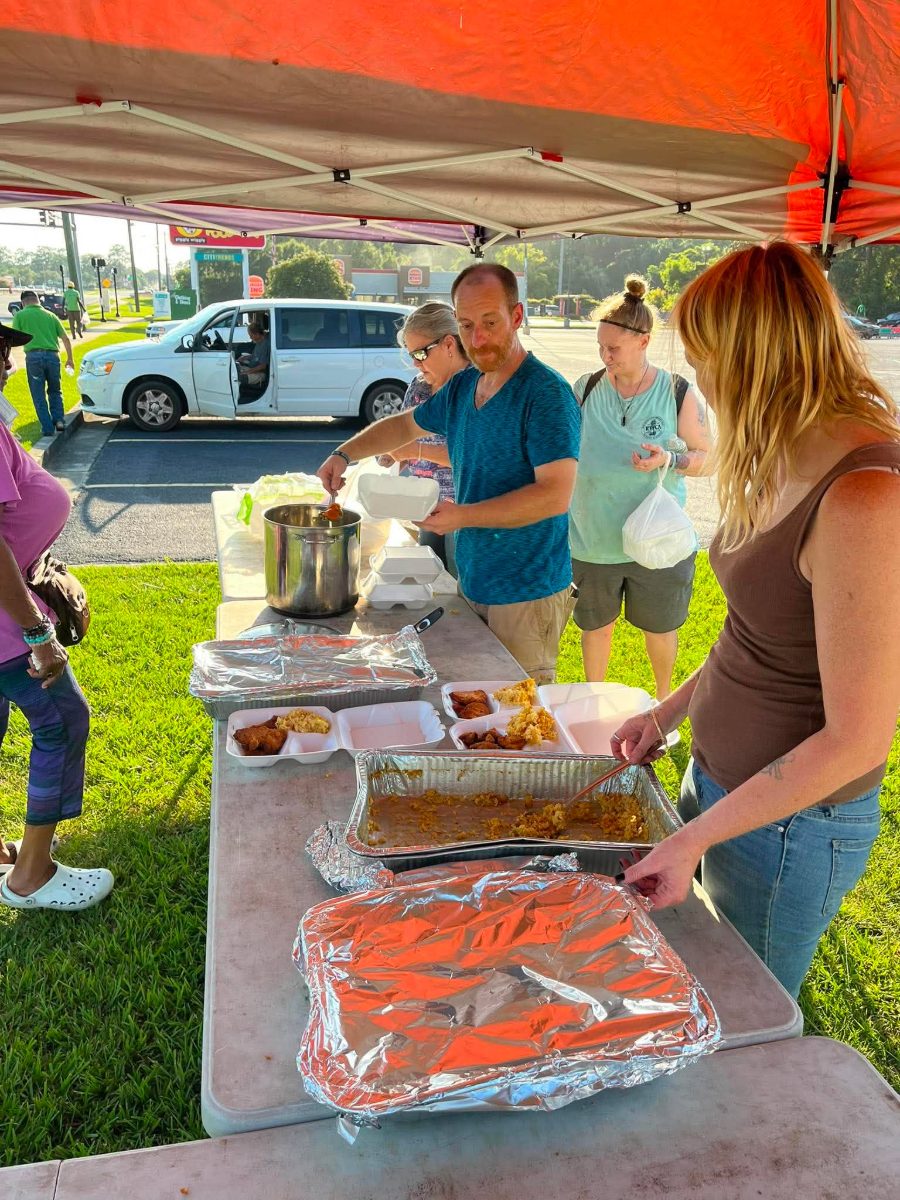 Volunteers serving plates from foil trays at a Moultrie Street Feed