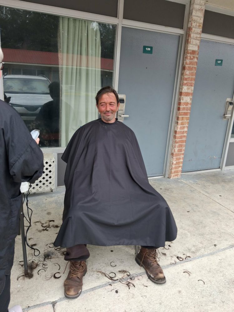 A man smiling after a fresh haircut on Tuesday Shower Day